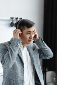 Testimonials Asian man in a call center wearing a headset, dressed in a gray suit, handling customer service calls.